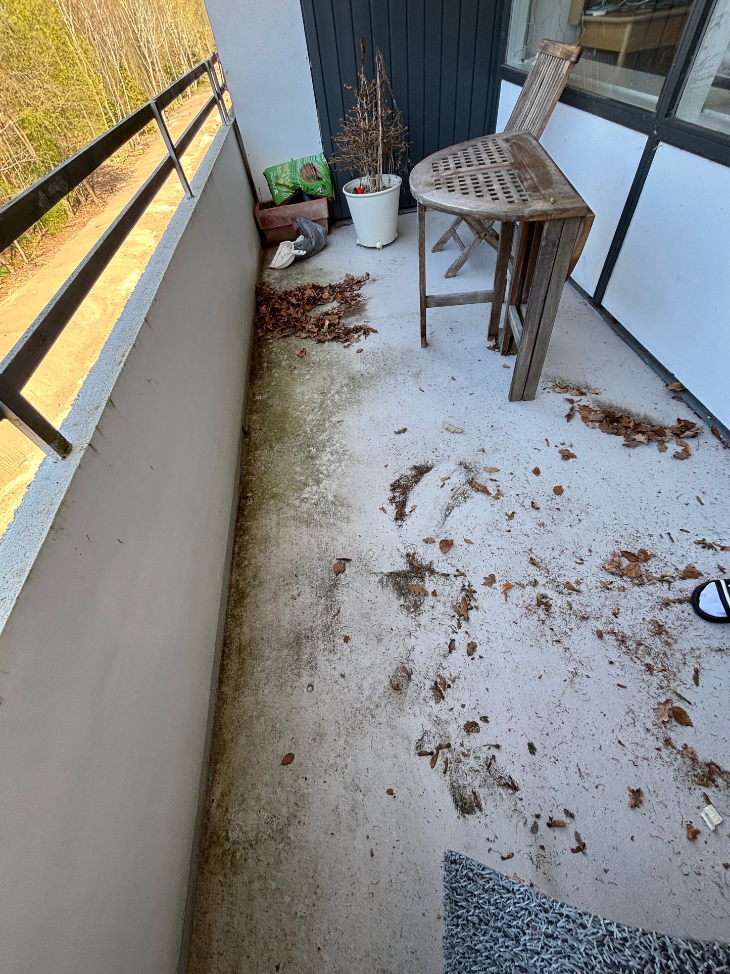 Messy balcony in need of cleaning, featuring leaves, dirt, and uneven surfaces in Copenhagen.