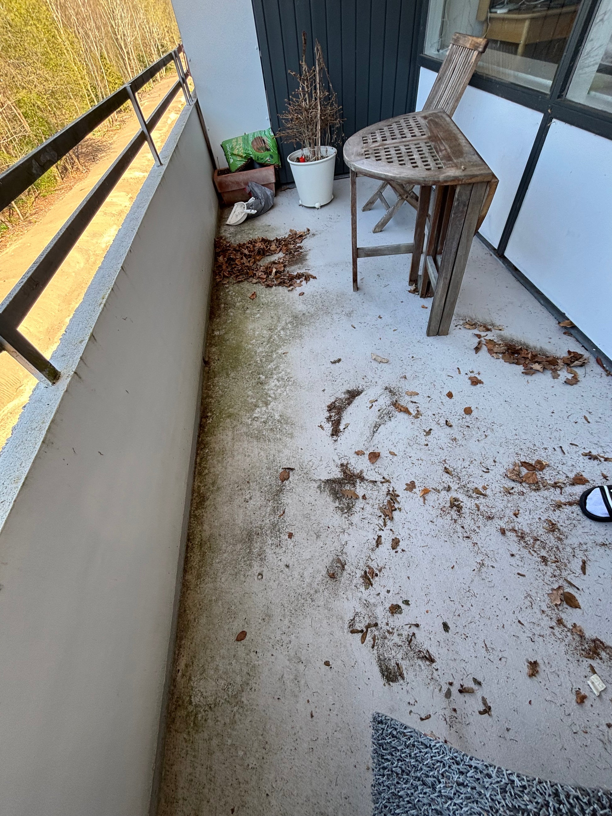 Messy balcony in need of cleaning, featuring leaves, dirt, and uneven surfaces in Copenhagen.
