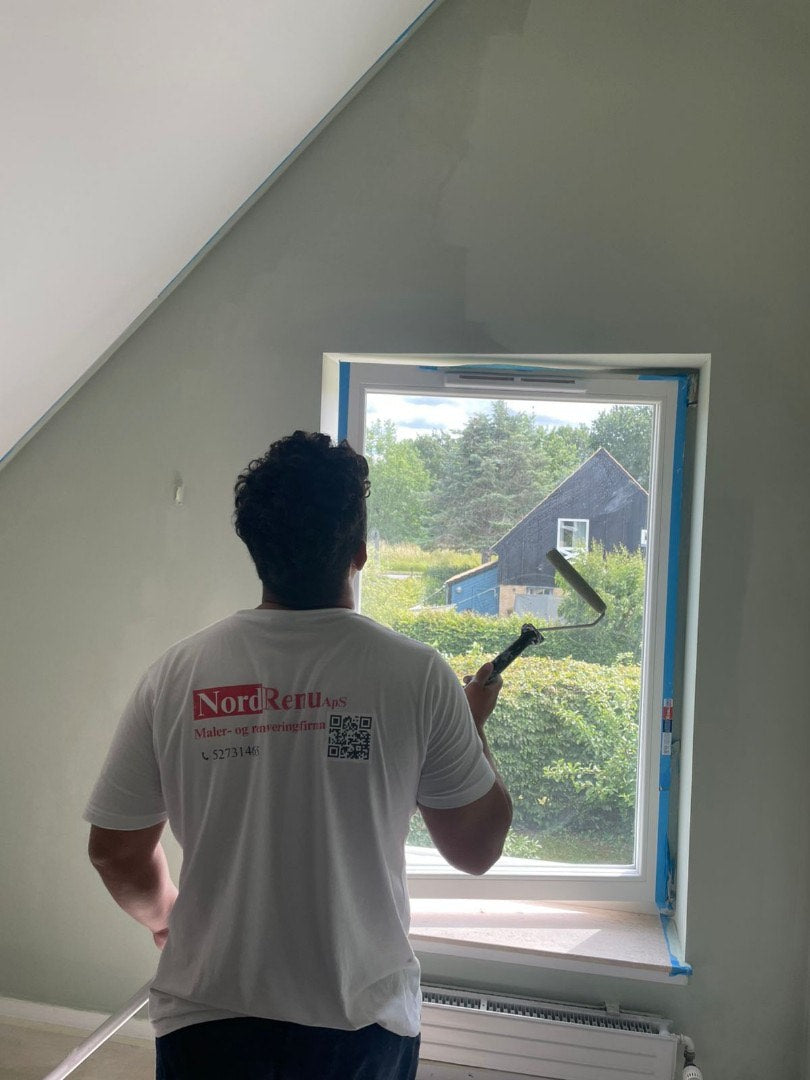Professional painter applying fresh paint in a Copenhagen home, showcasing expertise in wall painting services.