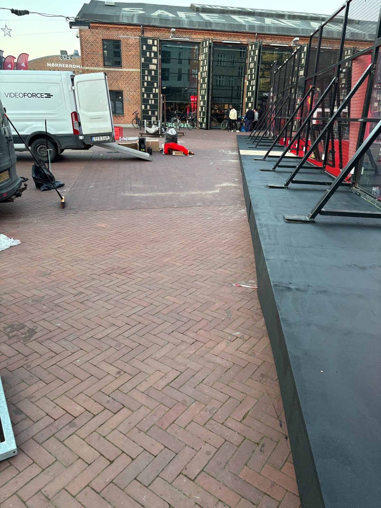 Outdoor event setup area showing pavement, vehicles, and preparation for an upcoming gathering.