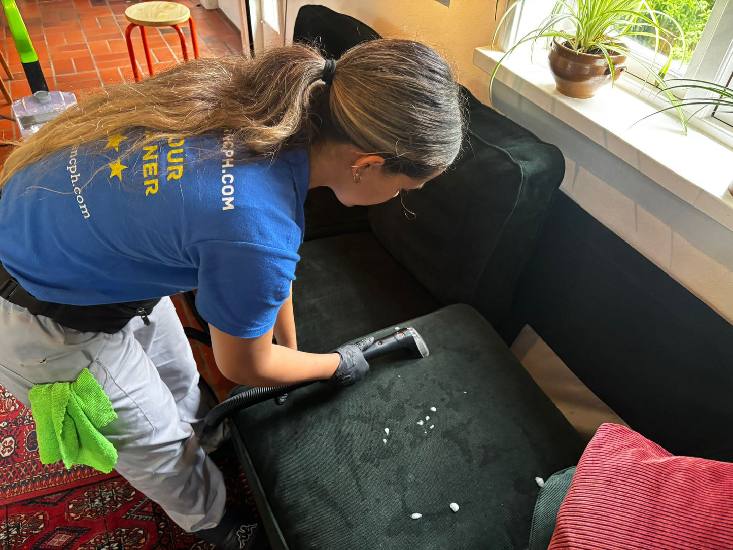 Professional cleaning service focusing on deep cleaning a sofa in a vibrant living room.
